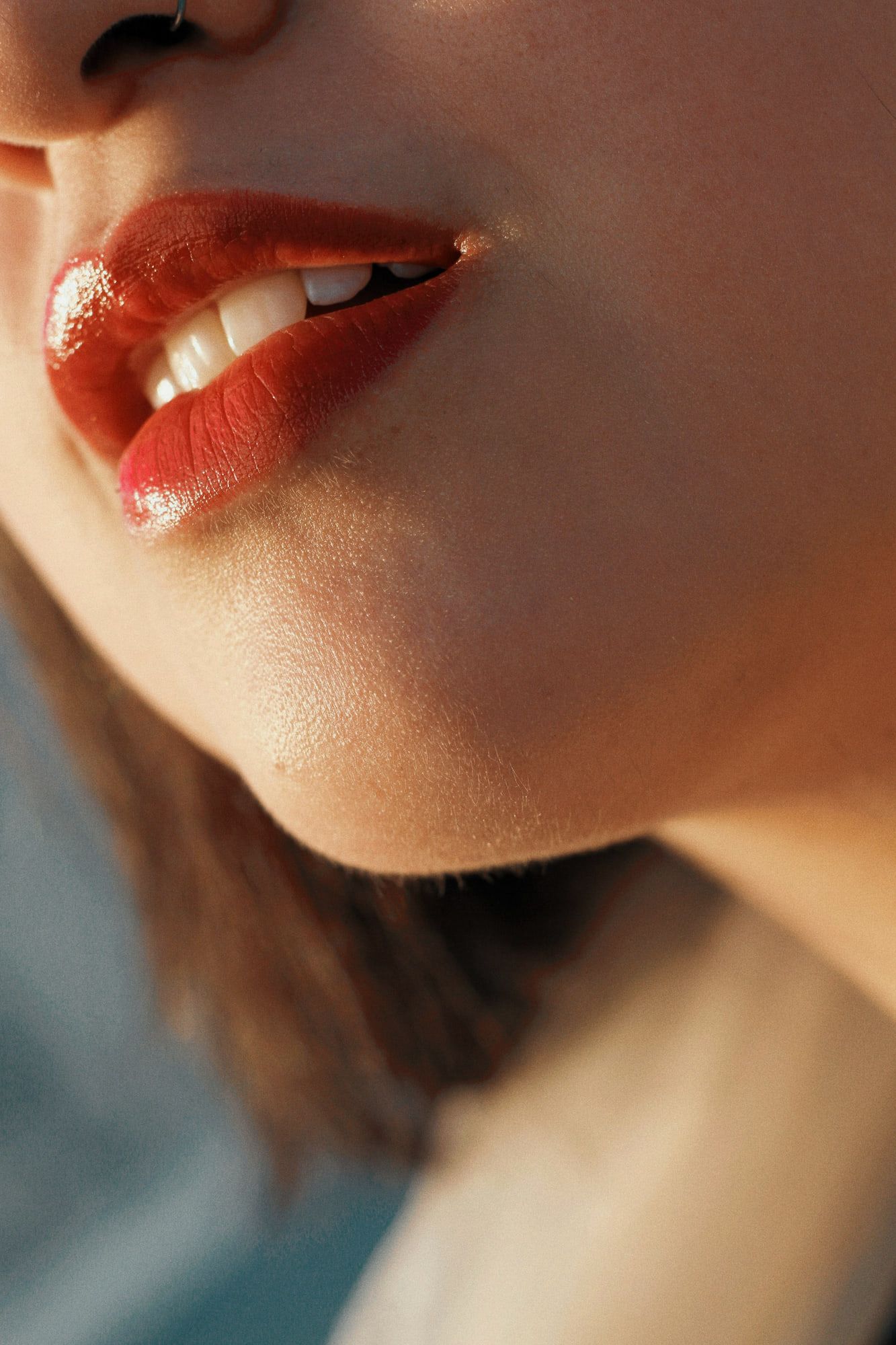 A mouth and jaw in warm light, the colour still glossy before it sets.